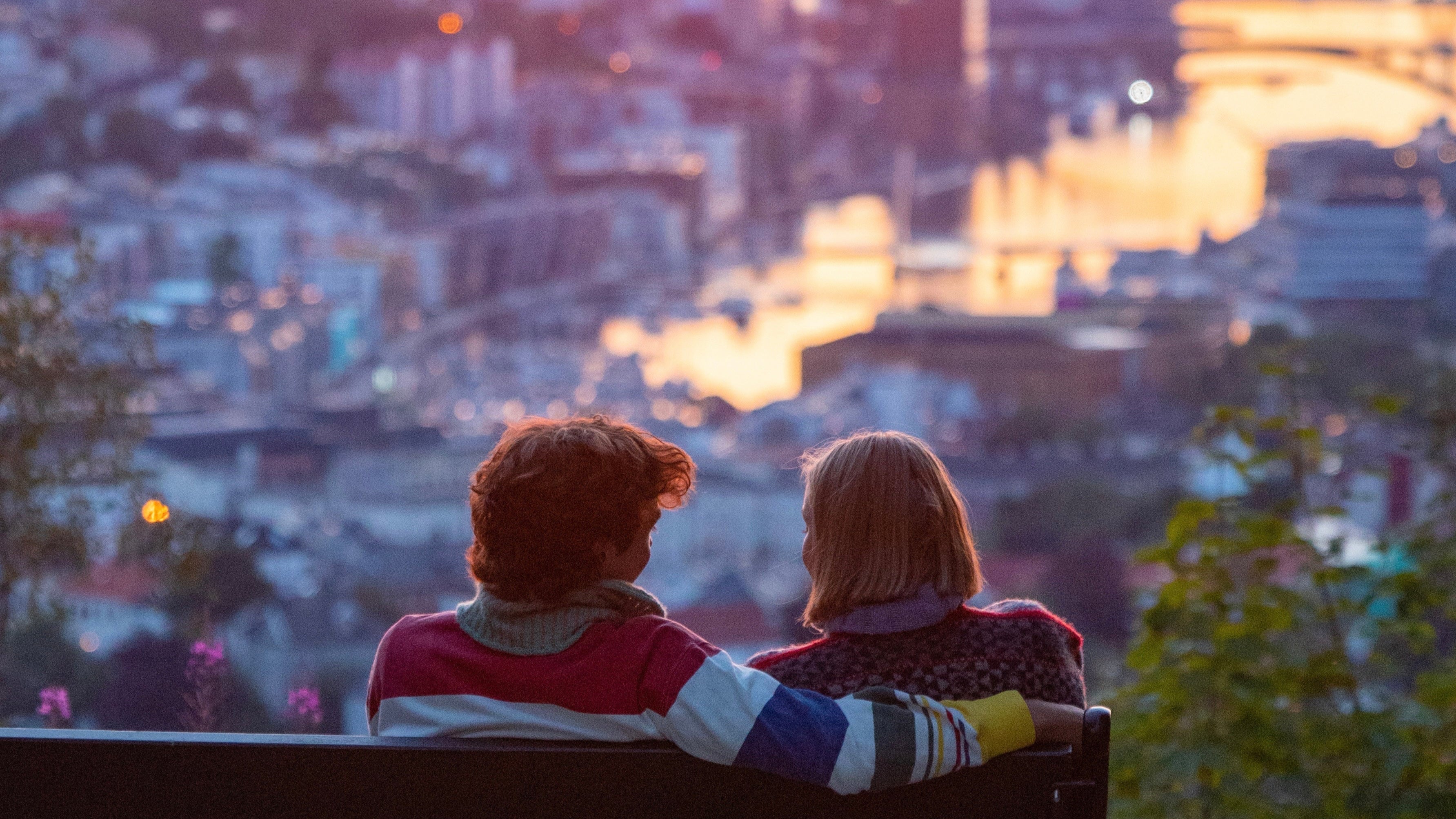 Two people sitting at a viewpoint in Bergen watching the sunset – photo from the Bergen travel guide.